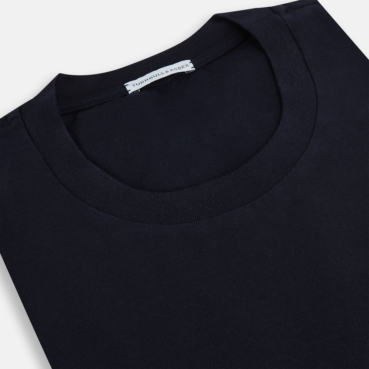 A navy short-sleeve pyjama shirt by Turnbull & Asser is laid flat on a white background, featuring a round neckline and a minimalist design—perfect for relaxed wear.